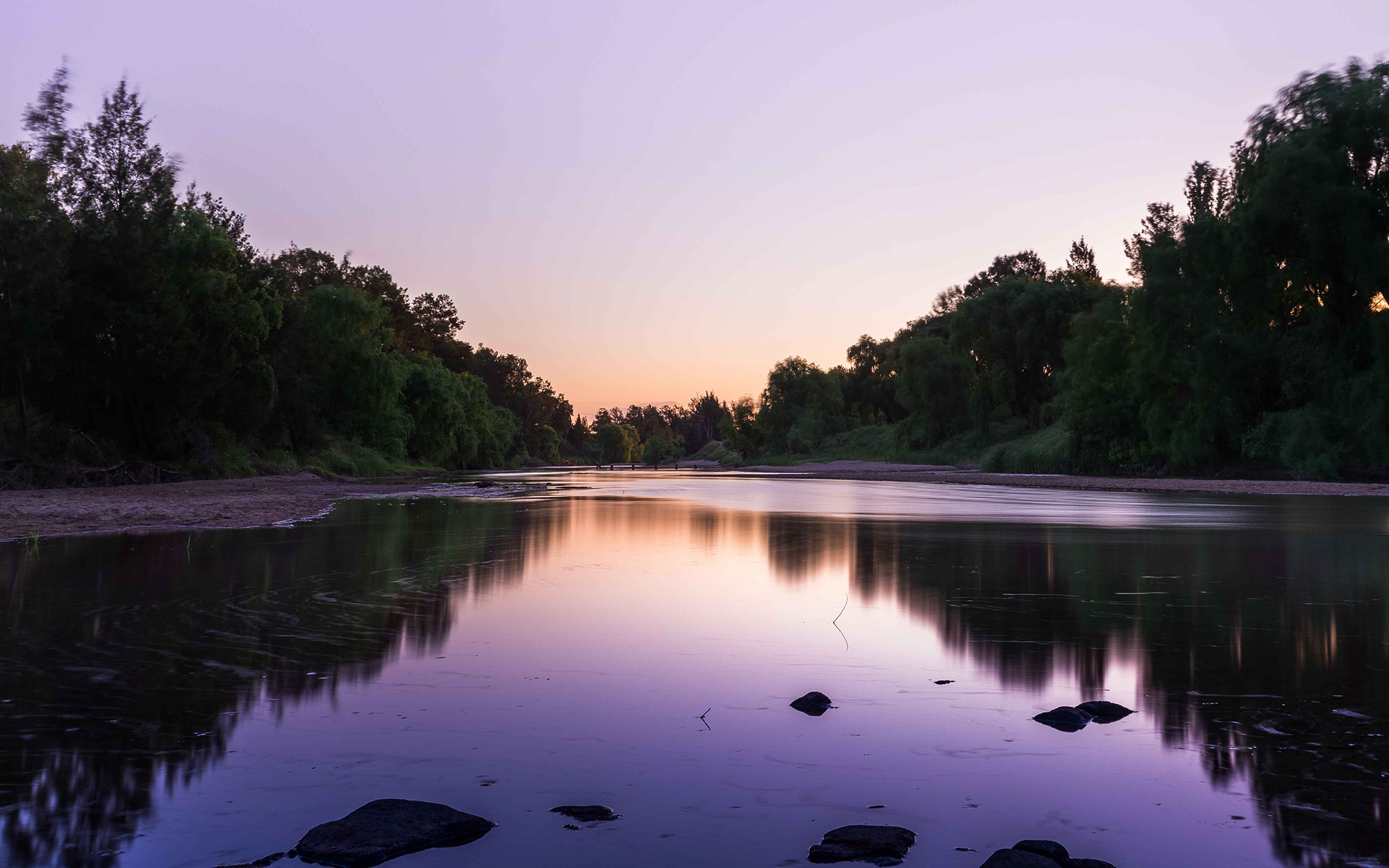 Purple sunset reflecting in the water at Aberglasslyn River Bank, New South Wales, Australia.