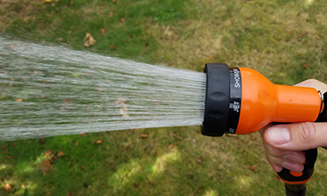 Water spraying from a hand-held hose.