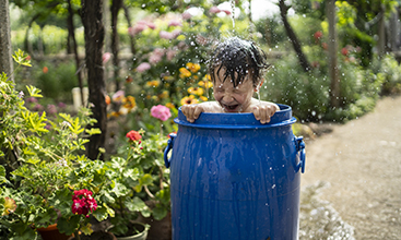 Boy having fun playing with water in the garden.