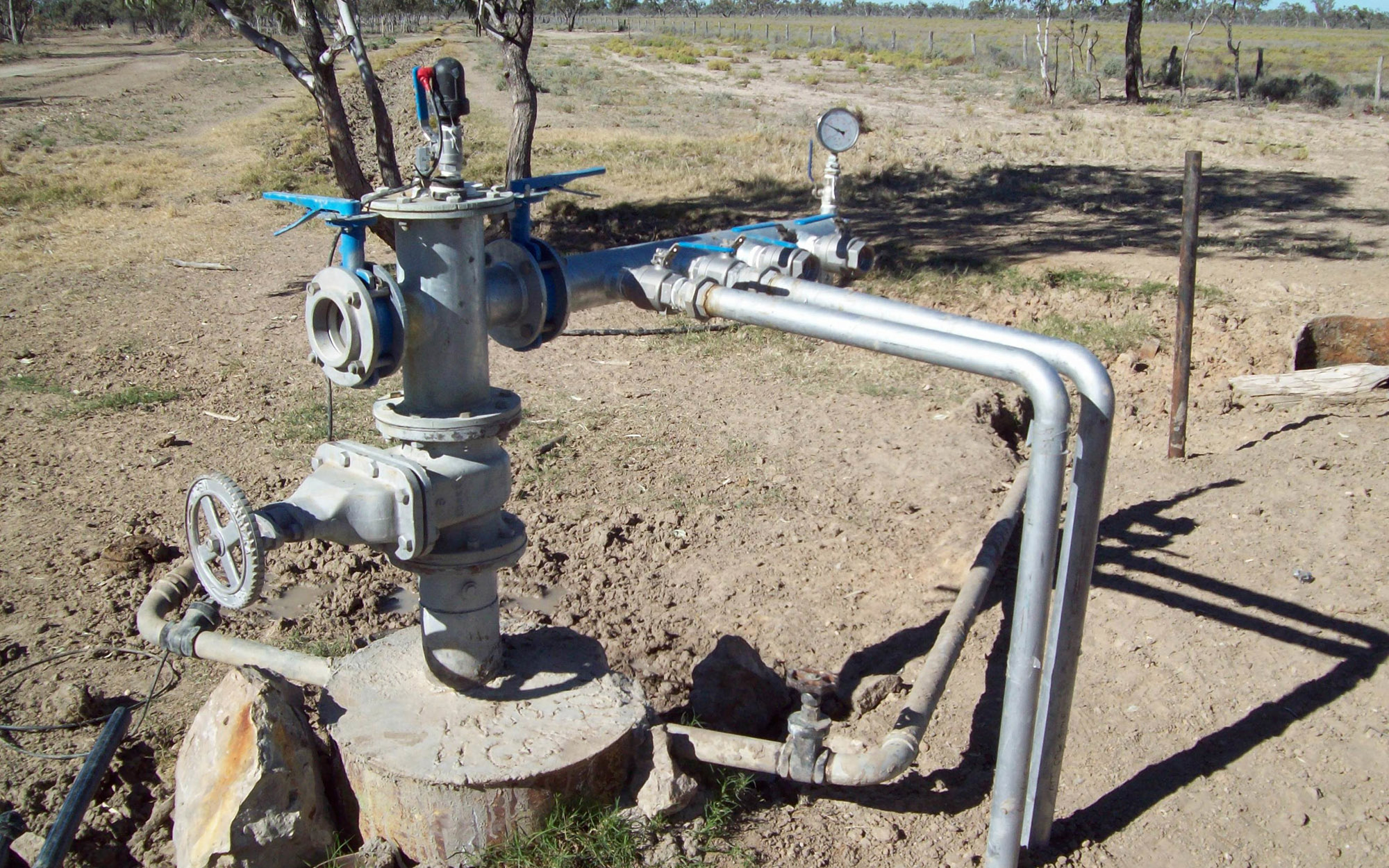 Bore pump in a paddock with dusty soil 